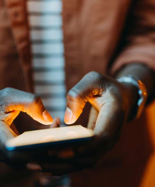 Black hands holding and typing on a mobile phone.