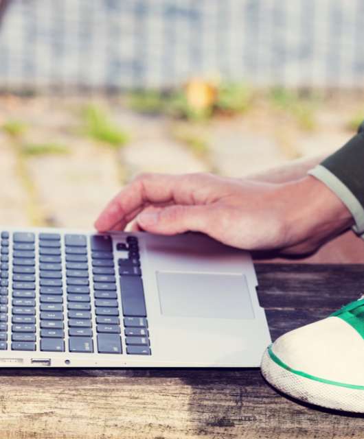 A person kneeling while using their laptop