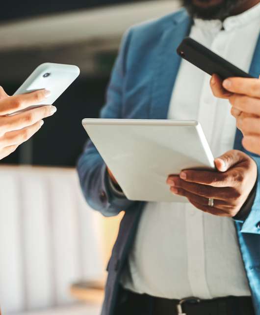 Three individuals looking at smart devices together.