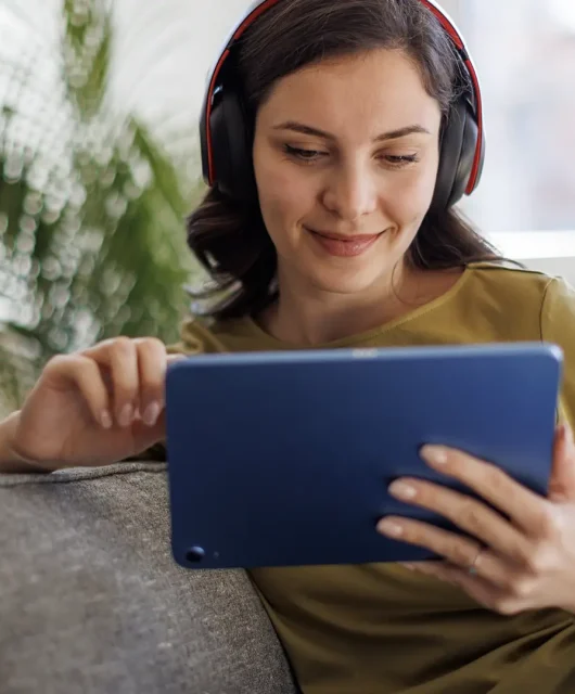 Woman sitting on a couch watching something on her tablet